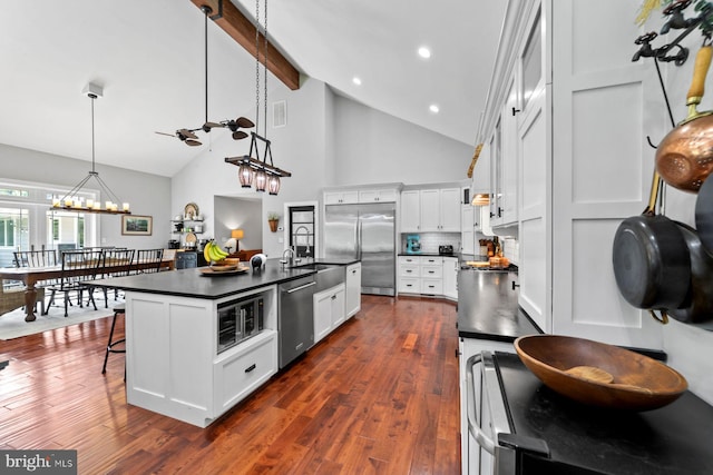65 Shady Brook Ln, Princeton, NJ 08540 - kitchen featuring appliances with stainless steel finishes, dark countertops, a center island with sink, white cabinetry, and a breakfast bar