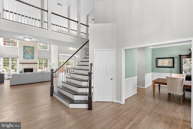43251 Brownstone Ct, Ashburn, VA 20147 - staircase featuring a high ceiling, wood finished floors, a brick fireplace, and wainscoting