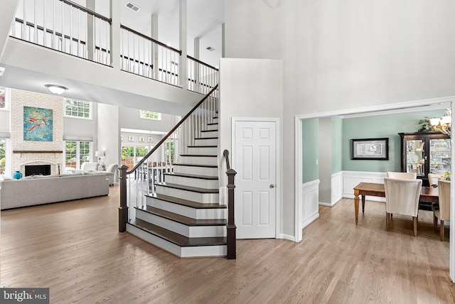 43251 Brownstone Ct, Ashburn, VA 20147 - stairs with a towering ceiling, wood finished floors, wainscoting, and a large fireplace
