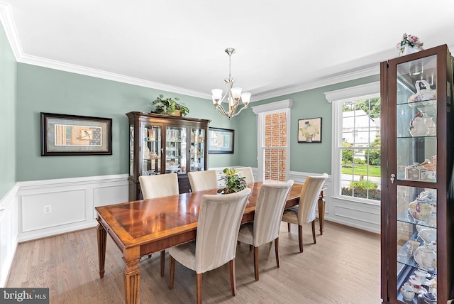43251 Brownstone Ct, Ashburn, VA 20147 - dining room featuring a chandelier, light wood-style floors, crown molding, wainscoting, and a decorative wall