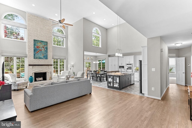 43251 Brownstone Ct, Ashburn, VA 20147 - living area with a large fireplace, a high ceiling, light wood-type flooring, ceiling fan, and recessed lighting