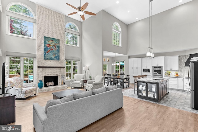 43251 Brownstone Ct, Ashburn, VA 20147 - living area featuring a fireplace, high vaulted ceiling, a ceiling fan, plenty of natural light, and light wood-style floors