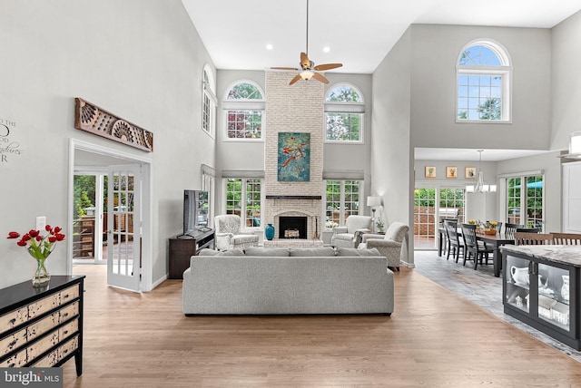 43251 Brownstone Ct, Ashburn, VA 20147 - living area with a towering ceiling, ceiling fan, light wood-style flooring, a brick fireplace, and recessed lighting