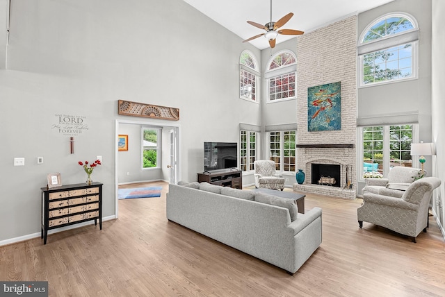 43251 Brownstone Ct, Ashburn, VA 20147 - living room featuring a brick fireplace, high vaulted ceiling, healthy amount of natural light, a ceiling fan, and light wood-type flooring