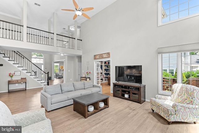 43251 Brownstone Ct, Ashburn, VA 20147 - living room featuring a towering ceiling, wood finished floors, a ceiling fan, stairs, and plenty of natural light