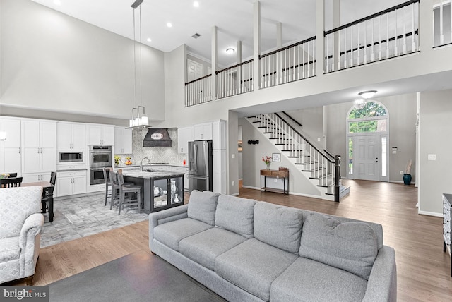 43251 Brownstone Ct, Ashburn, VA 20147 - living room featuring a towering ceiling, stairway, light wood finished floors, and recessed lighting