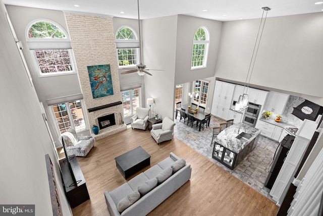 43251 Brownstone Ct, Ashburn, VA 20147 - living room featuring a high ceiling, a fireplace, recessed lighting, a ceiling fan, and light wood-type flooring