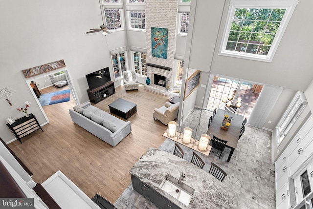 43251 Brownstone Ct, Ashburn, VA 20147 - living room with a high ceiling, ceiling fan, healthy amount of natural light, wood finished floors, and a fireplace