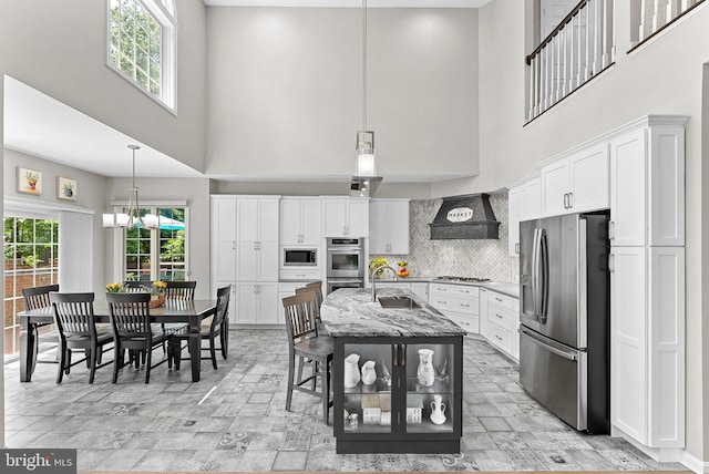 43251 Brownstone Ct, Ashburn, VA 20147 - kitchen featuring appliances with stainless steel finishes, premium range hood, a towering ceiling, healthy amount of natural light, and white cabinetry