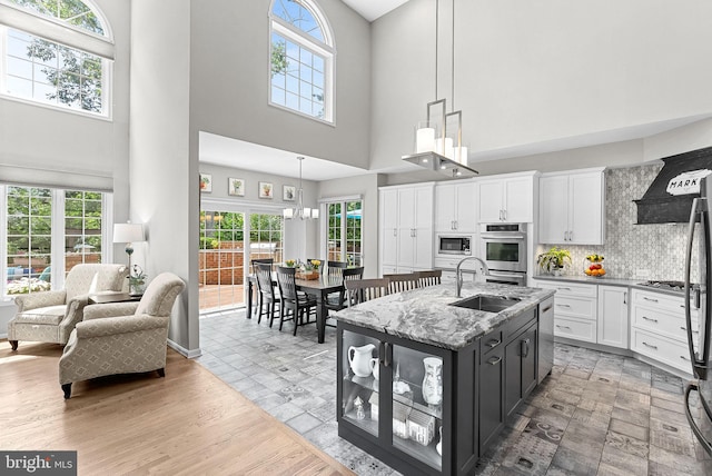 43251 Brownstone Ct, Ashburn, VA 20147 - kitchen with a high ceiling, stainless steel appliances, white cabinets, decorative light fixtures, and a kitchen island with sink