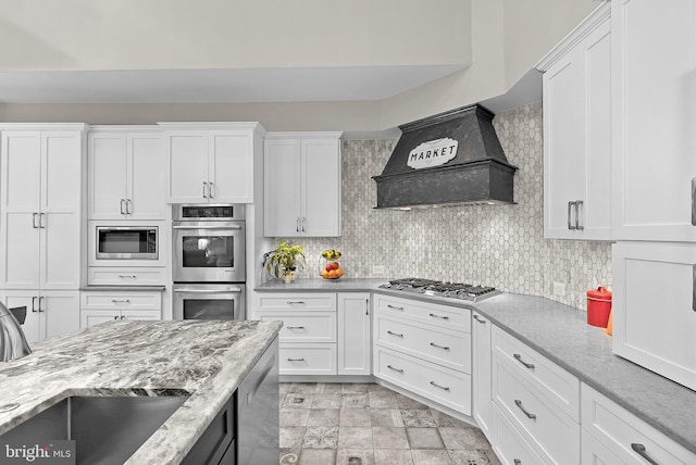 43251 Brownstone Ct, Ashburn, VA 20147 - kitchen featuring stainless steel appliances, premium range hood, white cabinets, and decorative backsplash