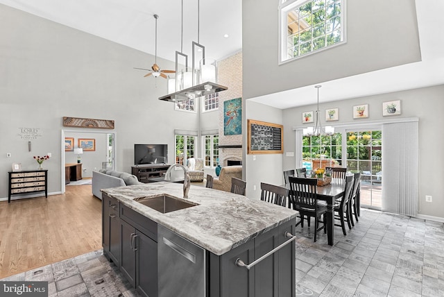 43251 Brownstone Ct, Ashburn, VA 20147 - kitchen featuring stainless steel dishwasher, ceiling fan, a high ceiling, a fireplace, and light stone countertops
