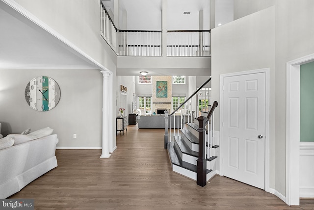 43251 Brownstone Ct, Ashburn, VA 20147 - foyer entrance with a towering ceiling, wood finished floors, a large fireplace, ornate columns, and stairway