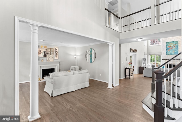 43251 Brownstone Ct, Ashburn, VA 20147 - living area with decorative columns, a high ceiling, ornamental molding, wood finished floors, and a fireplace