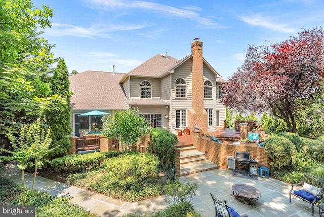 43251 Brownstone Ct, Ashburn, VA 20147 - rear view of property featuring a patio area, a fire pit, a chimney, roof with shingles, and a wooden deck