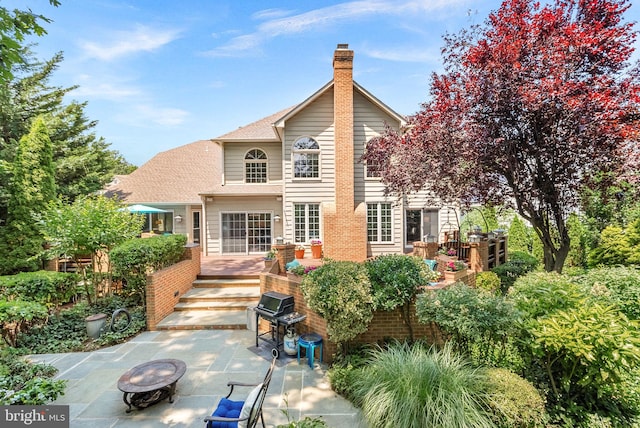 43251 Brownstone Ct, Ashburn, VA 20147 - back of property featuring a fire pit, a patio, a deck, a shingled roof, and brick siding