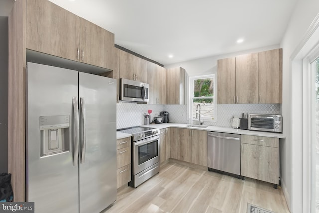 2246 N Hancock St, Philadelphia, PA 19133 - kitchen featuring stainless steel appliances, light countertops, light wood-type flooring, tasteful backsplash, and light brown cabinetry