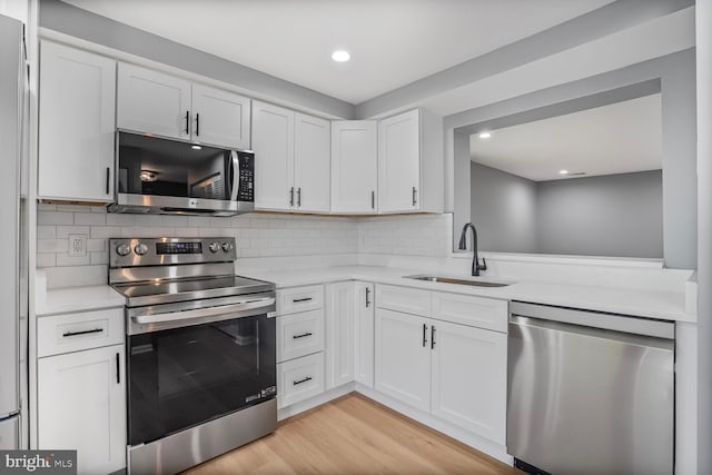4730 Still Pl, Woodbridge, VA 22193 - kitchen featuring stainless steel appliances, light countertops, white cabinetry, light wood-type flooring, and decorative backsplash