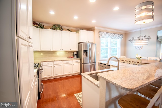 37126 Solitude Dr, Selbyville, DE 19975 - kitchen featuring stainless steel appliances, crown molding, a kitchen bar, decorative backsplash, and light wood-style flooring