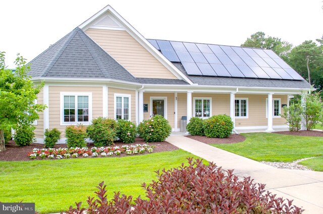 37126 Solitude Dr, Selbyville, DE 19975 - view of front of house featuring roof mounted solar panels, a front lawn, a shingled roof, and covered porch
