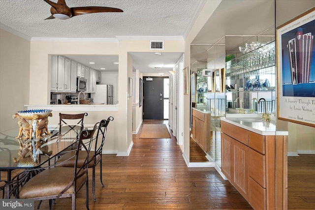 403 N Edgewater House Rd Unit 403N, Bethany Beach, DE 19930 - bar with appliances with stainless steel finishes, dark wood-type flooring, a ceiling fan, a textured ceiling, and crown molding