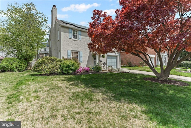 809 Addingham Ave, Drexel Hill, PA 19026 - view of front of house featuring a garage, roof mounted solar panels, a front yard, and a chimney
