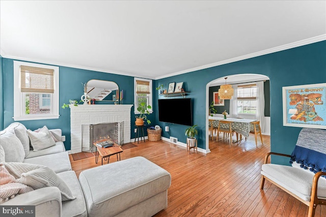 809 Addingham Ave, Drexel Hill, PA 19026 - living room with a brick fireplace, crown molding, hardwood / wood-style floors, and arched walkways