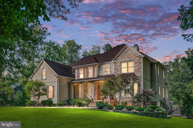 11204 Fawn Lake Pkwy, Spotsylvania, VA 22551 - traditional-style house with stone siding, a chimney, a lawn, and stucco siding