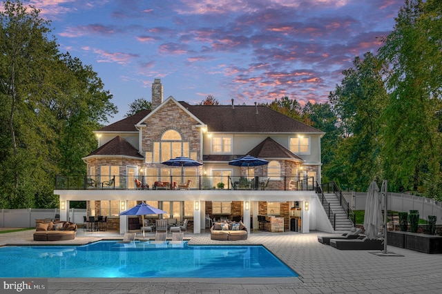 11204 Fawn Lake Pkwy, Spotsylvania, VA 22551 - back of house at dusk with an outdoor hangout area, a balcony, stairs, and stone siding