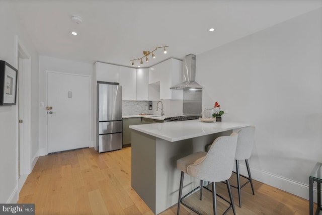 2829 Connecticut Ave NW Unit 706, Washington, DC 20008 - kitchen with freestanding refrigerator, wall chimney exhaust hood, a peninsula, white cabinets, and light countertops