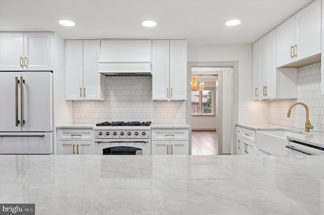 4127 Presidential Dr, Lafayette Hill, PA 19444 - kitchen with high quality appliances, custom exhaust hood, light stone counters, white cabinetry, and tasteful backsplash