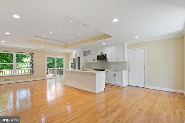 11013 Lopa Ln, North Potomac, MD 20878 - kitchen featuring appliances with stainless steel finishes, crown molding, a raised ceiling, white cabinetry, and backsplash