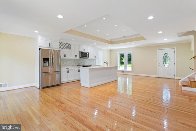 11013 Lopa Ln, North Potomac, MD 20878 - kitchen with appliances with stainless steel finishes, ornamental molding, a tray ceiling, white cabinetry, and light wood-type flooring