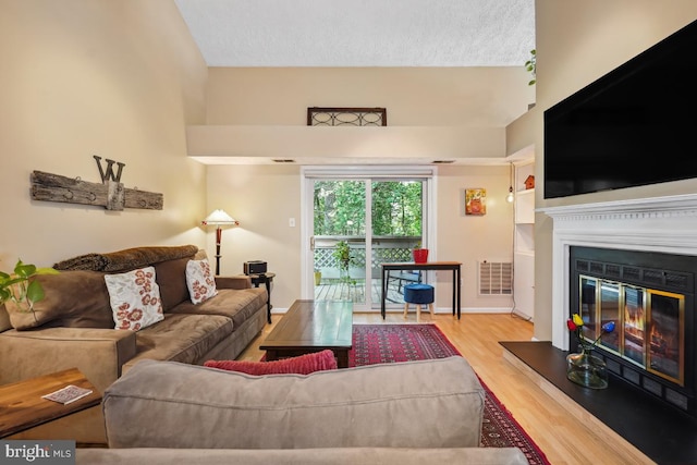 84 Windbrooke Cir Unit 84, Gaithersburg, MD 20879 - living room featuring a glass covered fireplace, wood finished floors, a textured ceiling, and lofted ceiling