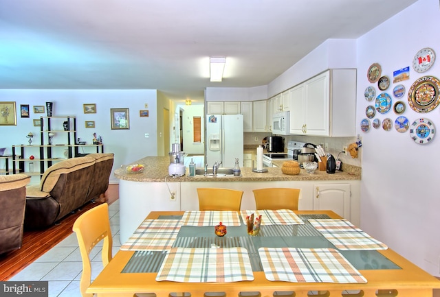 300 Bonnie Meadow Cir, Reisterstown, MD 21136 - kitchen with white appliances, a peninsula, white cabinets, light tile patterned floors, and backsplash