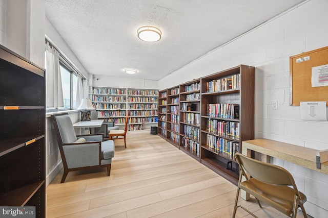 4515 Willard Ave Unit 1111S, Chevy Chase, MD 20815 - living area featuring bookshelves, a textured ceiling, wood finished floors, and concrete block wall