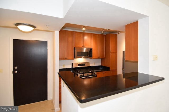 851 N Glebe Rd Unit 1418, Arlington, VA 22203 - kitchen featuring appliances with stainless steel finishes, dark countertops, brown cabinetry, a peninsula, and light tile patterned floors