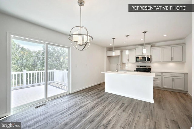 6329 Liam Dr Lot 54, Spring Grove, PA 17362 - kitchen with stainless steel microwave, range with electric cooktop, light wood finished floors, hanging light fixtures, and a chandelier