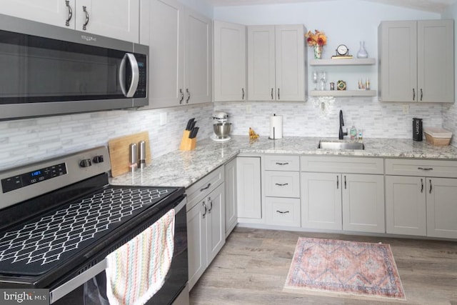 213 Conover St, Burlington, NJ 08016 - kitchen featuring appliances with stainless steel finishes, light wood-type flooring, tasteful backsplash, open shelves, and light stone countertops