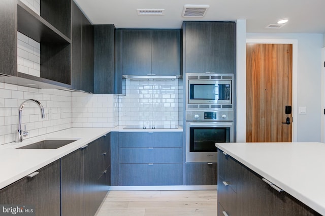 1300 4th St SE Unit 908, Washington, DC 20003 - kitchen featuring appliances with stainless steel finishes, light countertops, under cabinet range hood, backsplash, and modern cabinets