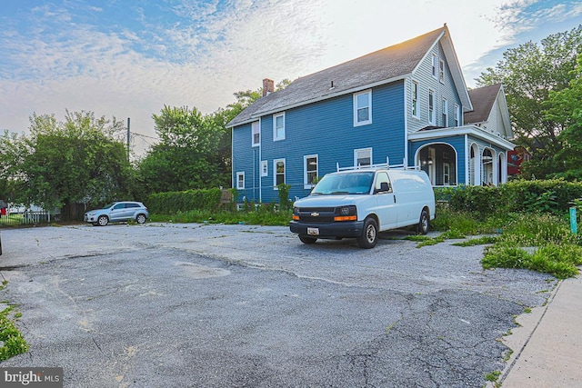 604 E 31st St, Baltimore, MD 21218 - view of home's exterior featuring a chimney and uncovered parking