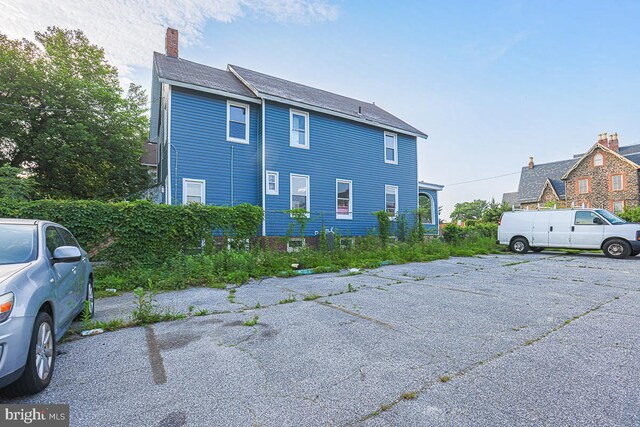 604 E 31st St, Baltimore, MD 21218 - view of side of home featuring a chimney and uncovered parking