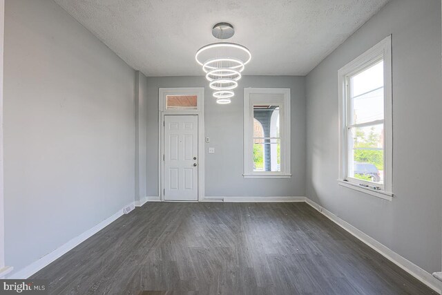 604 E 31st St, Baltimore, MD 21218 - unfurnished dining area with dark wood-type flooring, a chandelier, and a textured ceiling