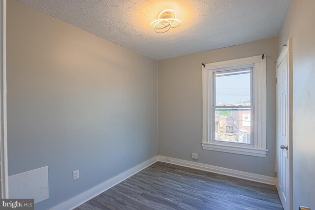 604 E 31st St, Baltimore, MD 21218 - empty room featuring dark wood finished floors and a textured ceiling