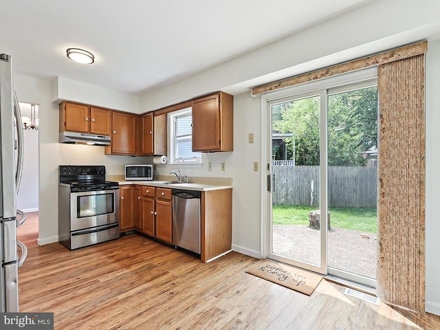 1035 Deerfield Cir, Perkasie, PA 18944 - kitchen featuring stainless steel appliances, under cabinet range hood, light wood-style flooring, light countertops, and brown cabinetry