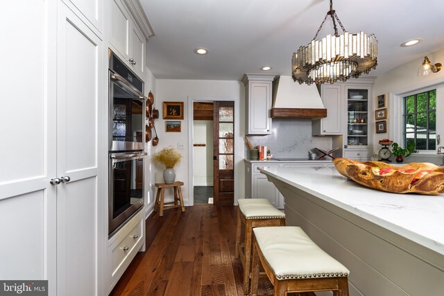 1032 N New St, West Chester, PA 19380 - kitchen with premium range hood, double oven, dark wood-type flooring, a chandelier, and decorative light fixtures