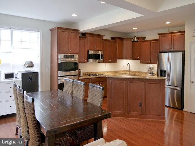 15152 Santander Dr, Gainesville, VA 20155 - kitchen featuring stainless steel appliances, brown cabinetry, a kitchen island, wood finished floors, and recessed lighting