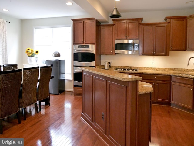 15152 Santander Dr, Gainesville, VA 20155 - kitchen with appliances with stainless steel finishes, dark wood-type flooring, a kitchen island, brown cabinetry, and recessed lighting