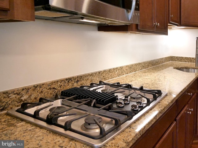 15152 Santander Dr, Gainesville, VA 20155 - kitchen view of stainless steel gas stovetop, dark brown cabinets, and light stone counters
