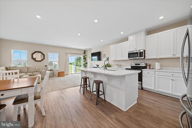 346 Goodwick Dr, Middletown, DE 19709 - kitchen with appliances with stainless steel finishes, open floor plan, wood finished floors, white cabinets, and a breakfast bar area